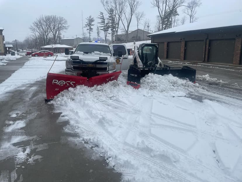 Snow plow trucks clearing parking lot